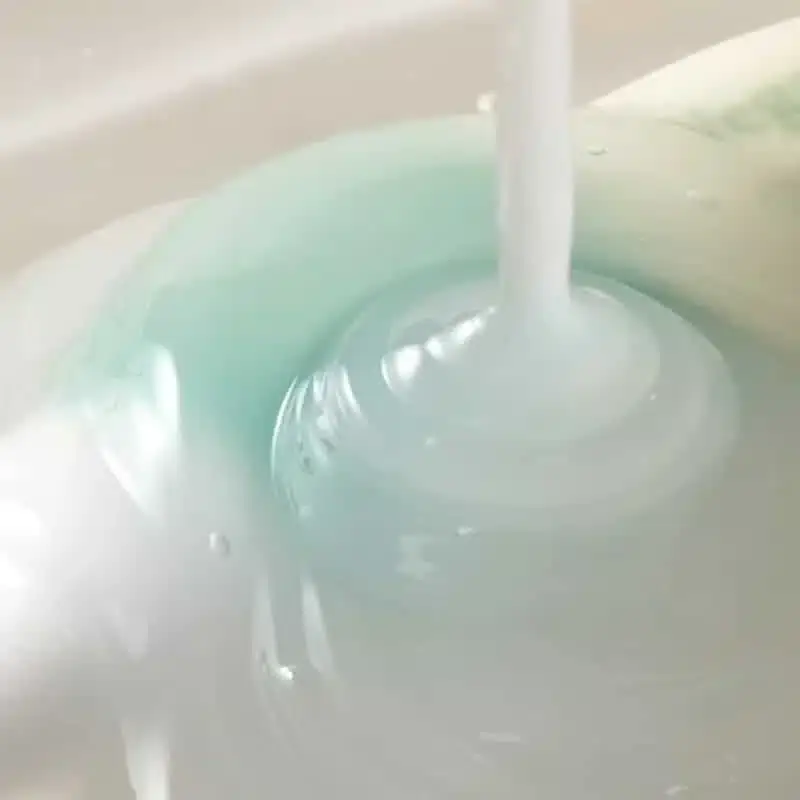 Close-up of Axis-y Vegan Collagen Eye Serum dropper dispensing clear serum onto skin. - thumbnail