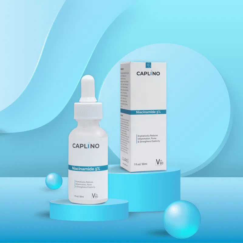 Hand holding Caplino Niacinamide Serum bottle, dropper dispensing clear liquid onto fingertips. - thumbnail