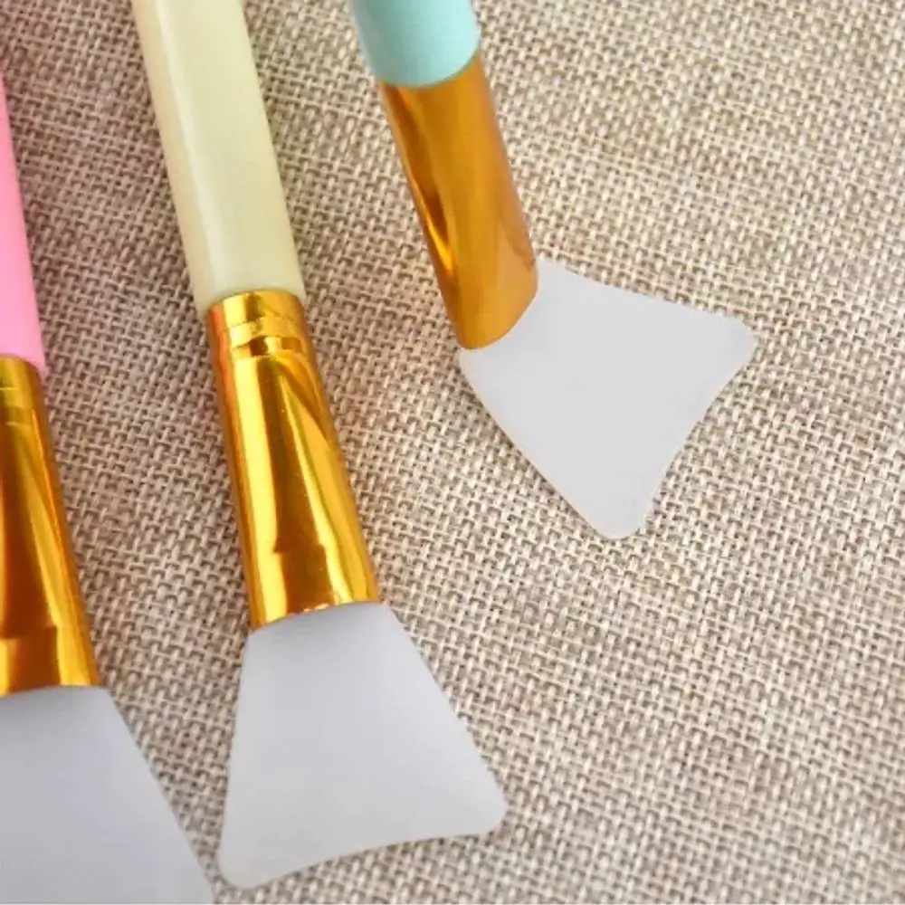 A hand gently holds the Laikou pink silicone facial mask applicator brush upright, highlighting its tip. - thumbnail