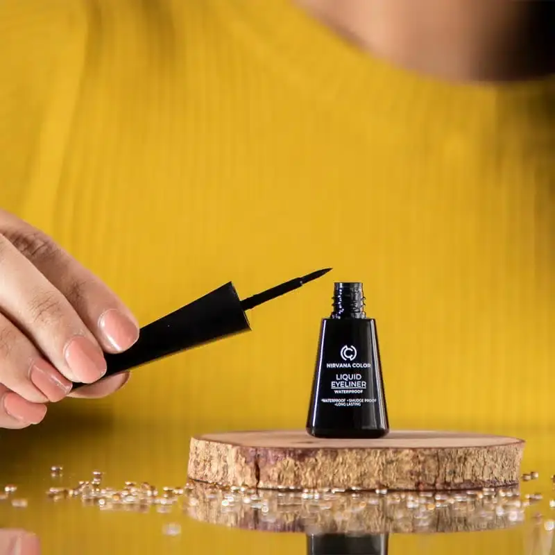 Hand holding Nirvana Eyeliner, demonstrating two intense deep black lines swatched on skin. - thumbnail