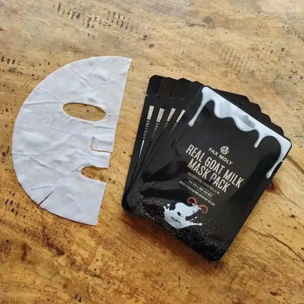 Two Pax Moly Goat Milk Sheet Masks; one open revealing the folded white mask inside. - thumbnail
