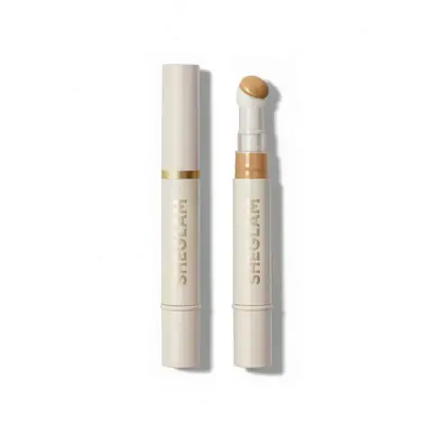 Sheglam Skin-fluencer Concealer in Sand shade, elegant tube with gold cap on white background.