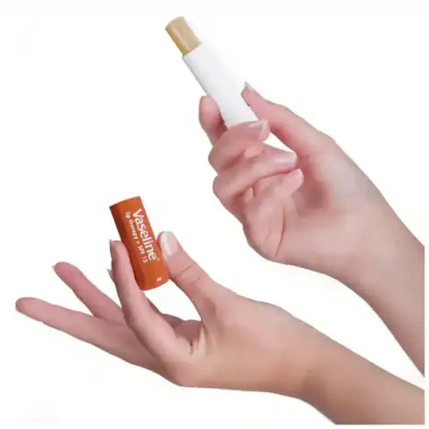 Vaseline Cocoa Butter Lip Care stick, yellow tube with brown cap, standing upright on white background.